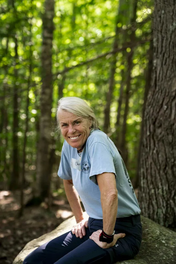 A smiling woman resting on a rock during a forest walk